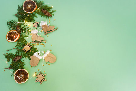 Wooden Christmas toys, thuja branches and dried orange slices on a green background. Christmas decorations. Flat lay. Eco friendly conceptの写真素材