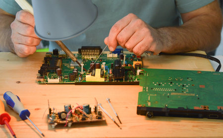 A man holds a soldering iron in his hand and solders a microcircuitの写真素材