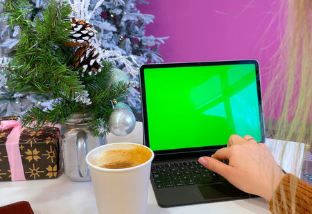 Working from home during the holidays. Working during Christmas. A computer with a mockup green...