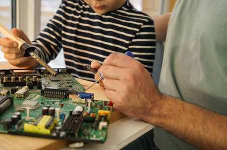 Father with his son spend time together. Close-up of a man teaching his boy at home to solder...