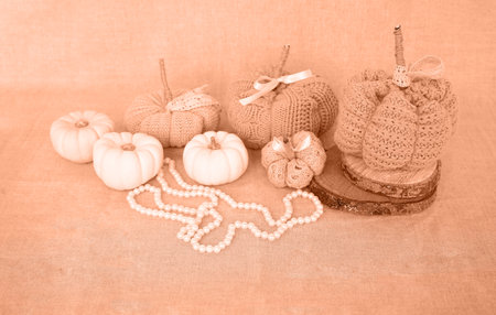 Hobby background with handmade knit pumpkins and white pearl beads. DIY, craft decoration for fall and winter holidays. Peach fuzz is color of year 2024 tinted imageの写真素材