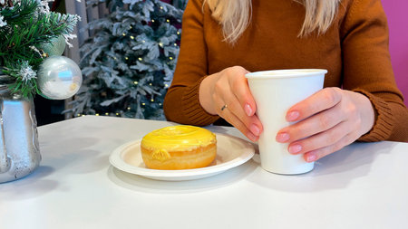 Woman with Christmas present, coffee cup and donut sitting at table in cafeの写真素材