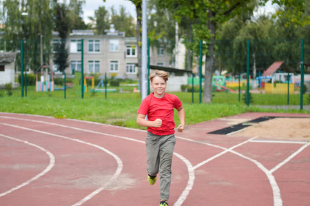 Attractive Caucasian boy runs around the stadiumの写真素材