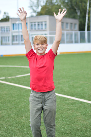 Child jumping on school stadium. Healthy outdoor exercise for children. Young athlete exercising. Sport for young boys.の写真素材