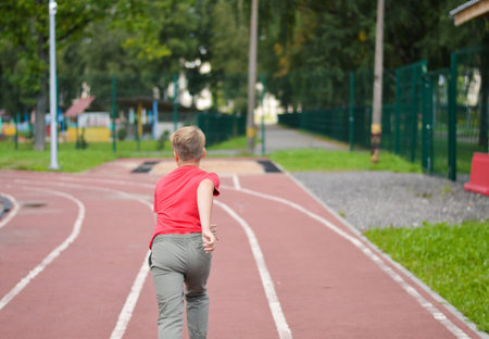 Caucasian boy runs around the stadiumの写真素材