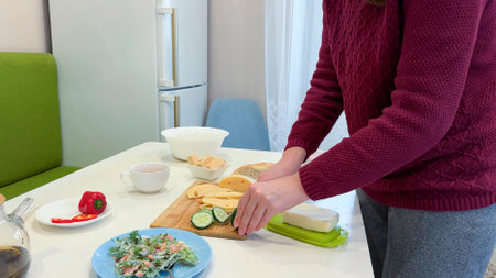 Close up cropped image of cutting board and couple cutting vegetables in the kitchen together, preparing food meal at home. Vegetarian healthy foodの写真素材