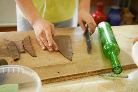 Craftsboy molds clay with rolling pin, closeup. Boy carefully rolls clay with pottery tools in the ceramic studioの写真素材