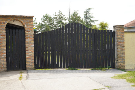 Wooden front gate of a beautiful luxury home. Fancy large mansion behind a locked gate. Nobody, street photo, selective focusの写真素材