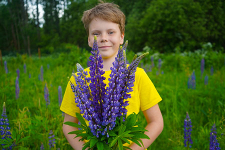 In a bright flower field, a happy boy in yellow is enjoying the outdoors with a big grin.