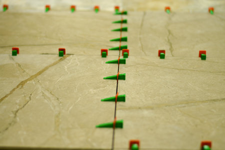 Each ceramic tile is meticulously set into the adhesive and then secured with the leveling system's components, which pull it flush with the surrounding tiles for a seamless lookの写真素材