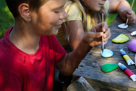 Young creators design cheerful scenes on found stones, turning simple objects into thoughtful, handmade presents.の写真素材