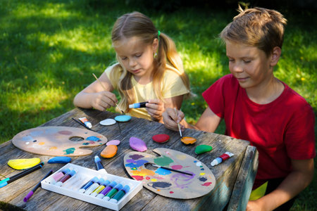 Using vibrant acrylics, children transform smooth, flat stones into colorful canvases for their imagination, creating perfect handmade gifts.の写真素材