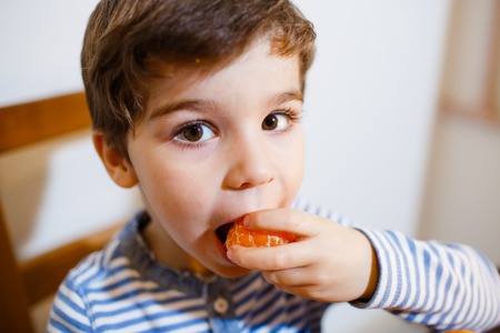 4-years boy eat a mandarin with great pleasureの写真素材