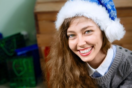 Portrait of a happy woman wearing a blue santa hatの写真素材