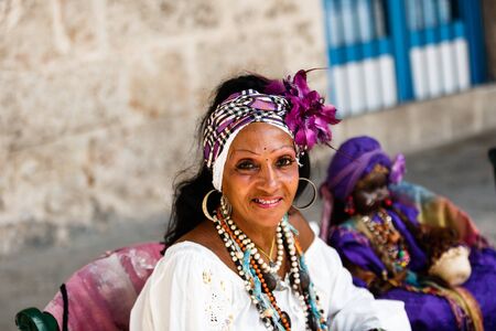 Dark-skinned Cuban in white costume tells fortunes to tourists in Havana streetsのeditorial素材