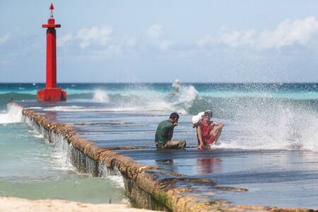 Cuban teenagers having fun sitting on pier of a lighthouse under spray of seaのeditorial素材