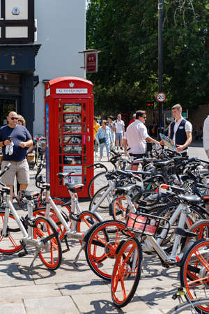 Cambridge, United Kingdom, July 23, 2019: Famous british Red phone booth and many bicycles near Cambridge Punters. Crowd of people, summer sunny dayのeditorial素材