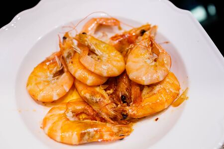 deep-sea shrimp fried in olive oil with garlic in a small frying pan on an induction electric panelの写真素材