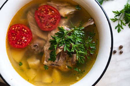 fish soup with carp, potatoes, parsley, tomato in enamel bowl stands on a boardの写真素材