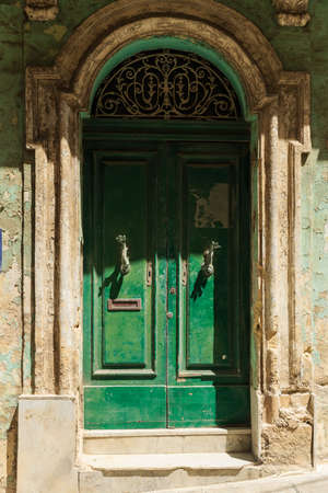dilapidated shabby green door on an old building. Fish-shaped door handlesの写真素材