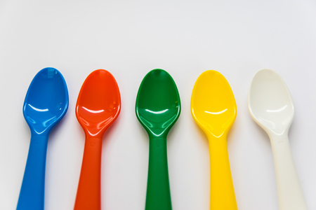 Multicolor plastic spoons on the white background. White, yellow, green, red, blue spoons can be used as a decorative elements or for food.の写真素材