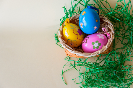 Easter color eggs in nature wicker basket on pastel background. Flat lay. Top view with copy space. Easter concept.の写真素材