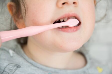 Cute little girl in bathroom cleaning the teeth with pink brush and pasta.の写真素材