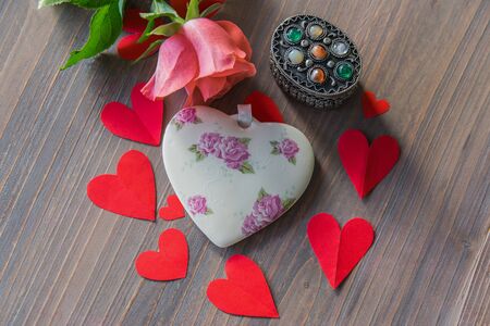 Porcelain heart with flowers on the wood textural table with pink flower and many red paper hearts around. Wedding or love sign. Flat lay.の写真素材