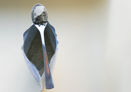 Metal spoon with green herbal powder with package on the light background.の写真素材