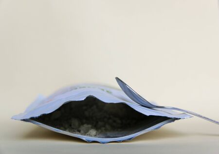 Metal spoon and green herbal powder in the package on the light background.の写真素材
