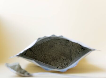 Green herbal powder in the package near with metal spoon on the light background.の写真素材