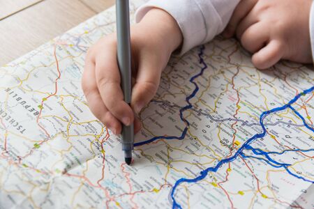 Hand of the child writing on a map with blue pen. Kids hand holding felt-tip pen. Travel and vacation  with children. Summer rest concept.の写真素材