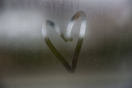 Beautiful heart love symbol on the glass window with water drobs.の写真素材