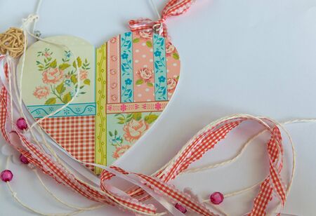 Wood lovely heart with ornament, tapes, beads on the white background. Flat lay. Handmade concept. Love sign for Valentines day.の写真素材