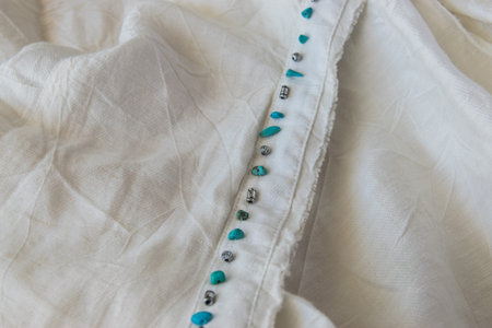 Beige cotton gentle texture clothes with decoration of turquoise natural stone. Textile cloth...
