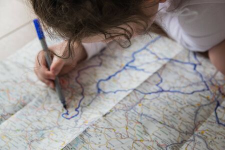 Hand of the child writing on a map with blue pen. Kids hand holding felt-tip pen. Travel and vacation  with children. Summer rest concept. の写真素材