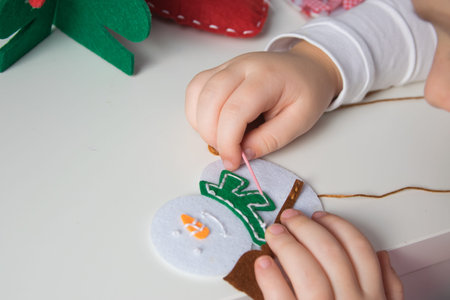 The hand of the child make snowman and christmas tree with needle, thread for christmas greeting...