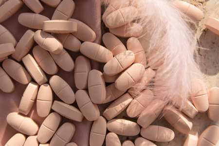 Pills or vitamins on the natural wood background with pink silk fabric and feather in summer day....