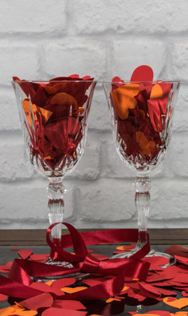Red paper hearts and red tape on the two glasses of champagne on stone structure background with...