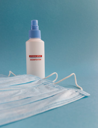 Disinfection spray and medical mask for hygiene on the blue background with place for text....