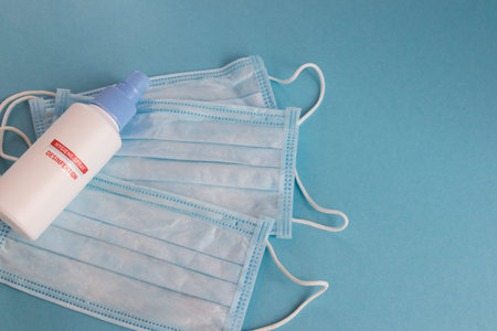 Disinfection spray and medical mask for hygiene on the blue background with place for text....