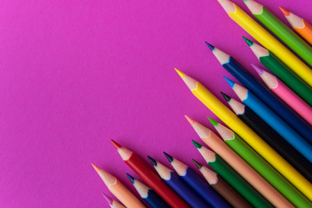 A lot of color pencils on the bright pink background. Close up. Design concept. Space for text.