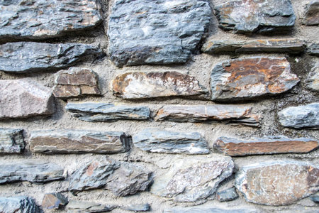 Gray structural stone wall of the ancient building consists of old dark bricks. Nature background.