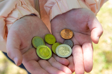 Child holding the coin on the hand in the middle of street.