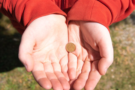 Child holding the coin on the hand in the middle of street.の写真素材
