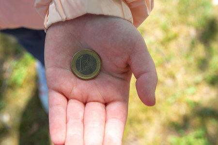 Child holding the coin on the hand in the middle of street.