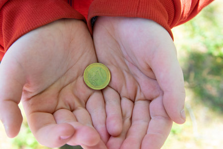 Coin one Euro holding the hand of child on the street.