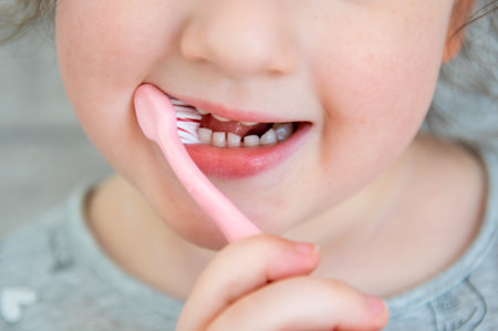 Cute little child in the bathroom cleaning the teeth with pink brush. Toothpaste concept. Healthy...