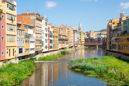 Beautiful street with historic houses, windows in the center of old town near little river. Spain, Girona.の写真素材