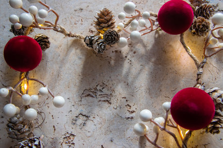 Beautiful bright Christmas background. Frame of cones, berries, tape, red balls for decor on the natural textured surface. Copy space. Top view.の写真素材